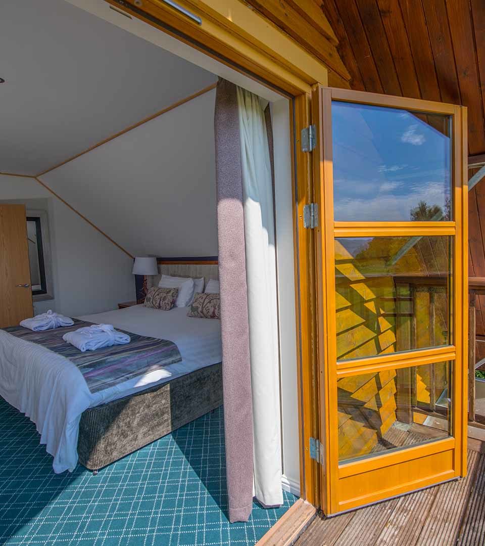 Looking into a double bedroom in a Diamond Lodge from the balcony at Loch Lomond Waterfront