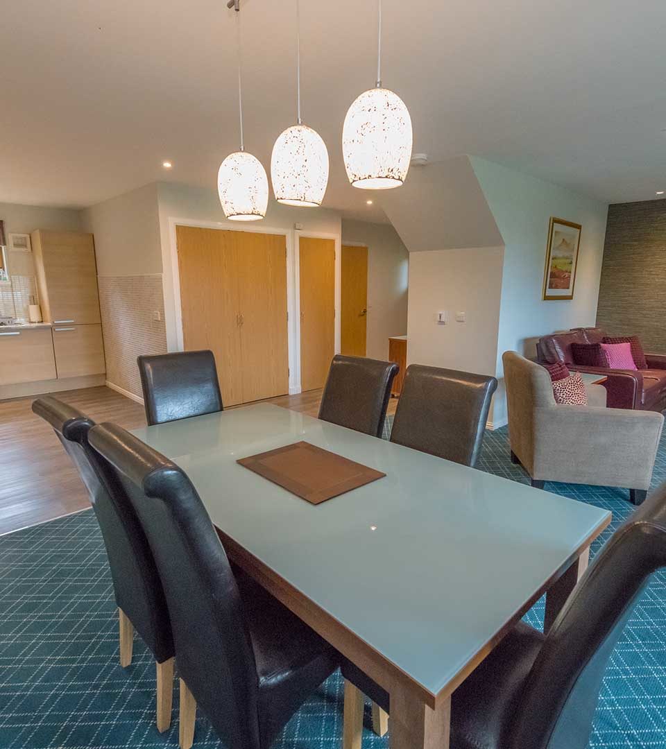 A dining area and living room in a lodge at Loch Lomond Waterfront