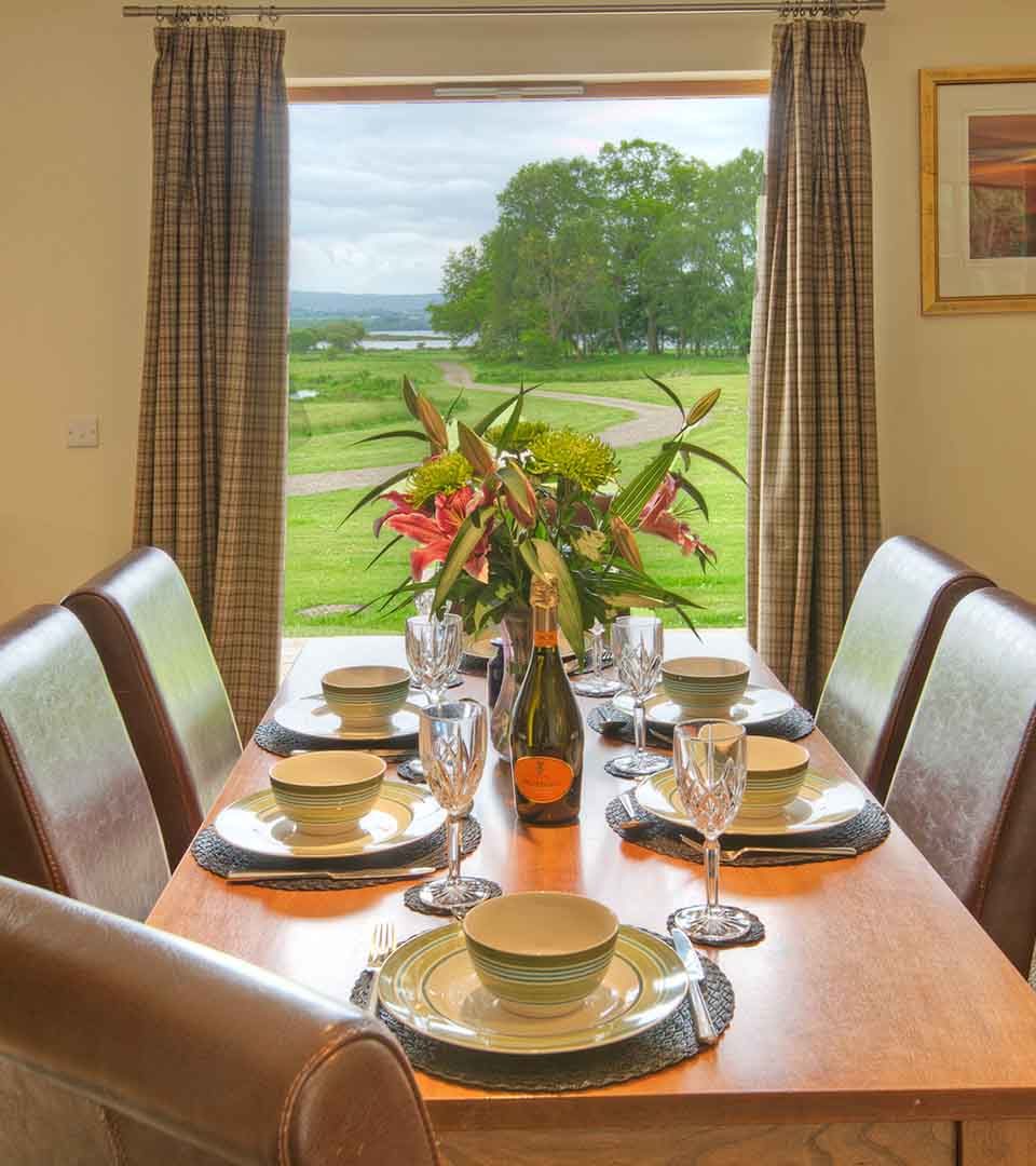 A dining table with a view out to Loch Lomond in a lodge at Loch Lomond Waterfront