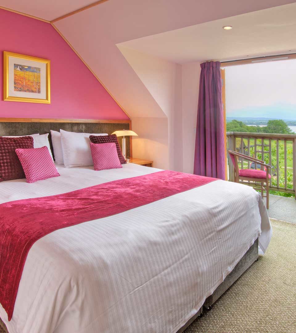 A double bedroom with a balcony with a view over Loch Lomond in a lodge at Loch Lomond Waterfront