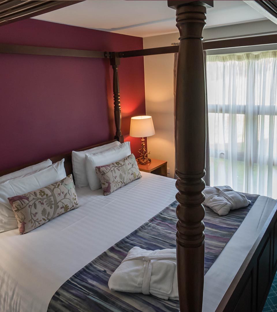 A large four poster bed in the Drummond / Honeymoon Suite chalet at Loch Lomond Waterfront in Balmaha