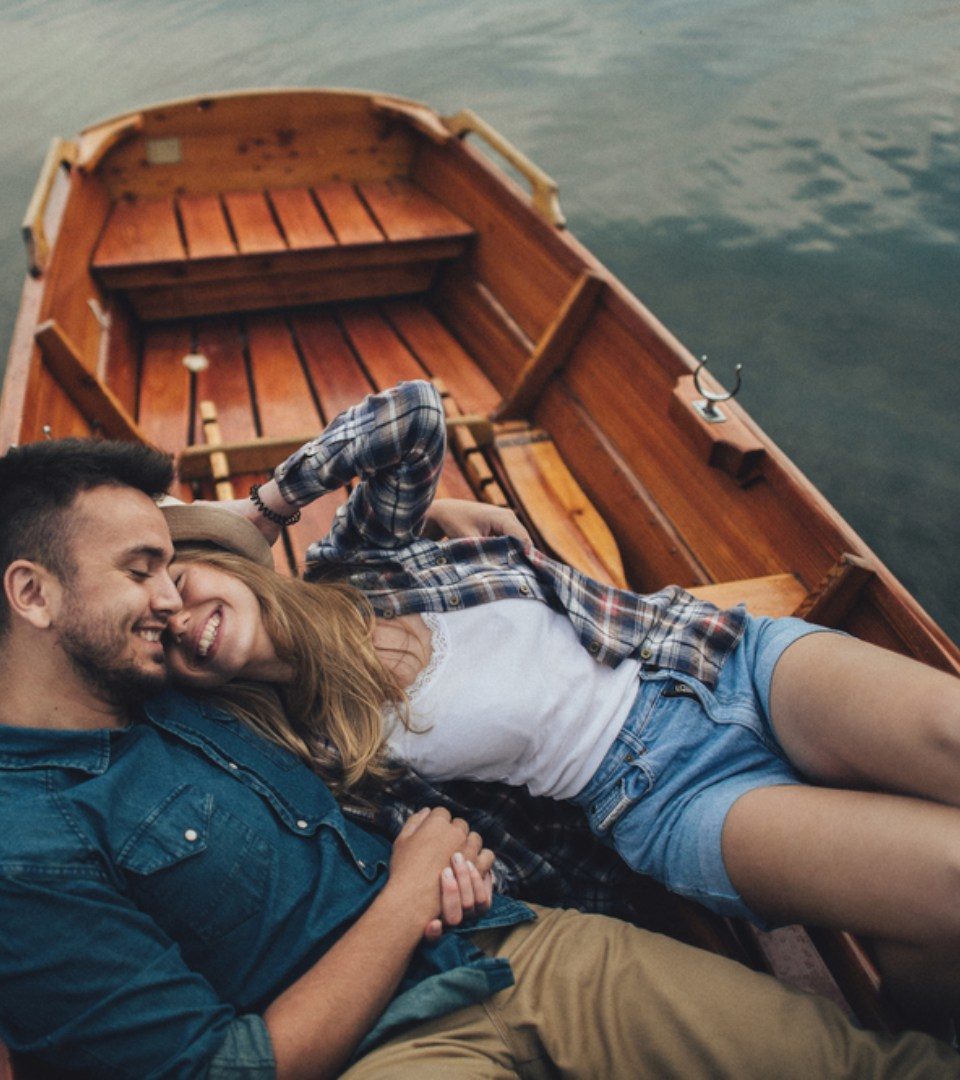 Couple cuddling and laughing floating on Loch Lomond in a boat