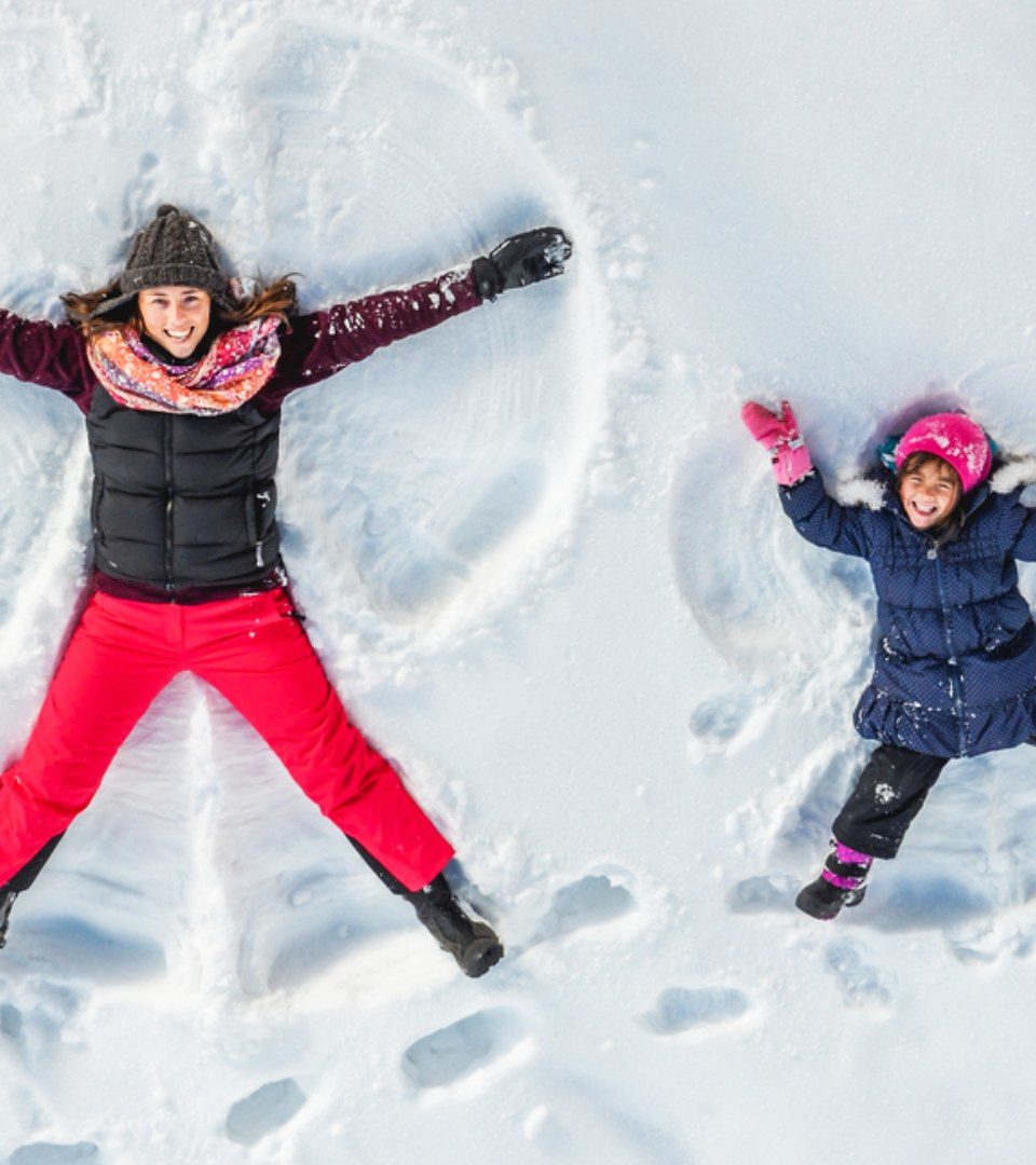 A lady and her little girl making snow angels