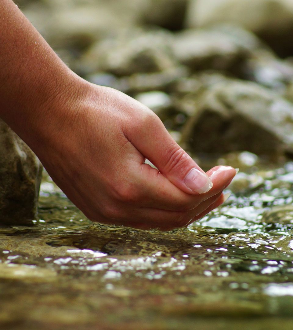 Hand reaching into the waters of a natural spring