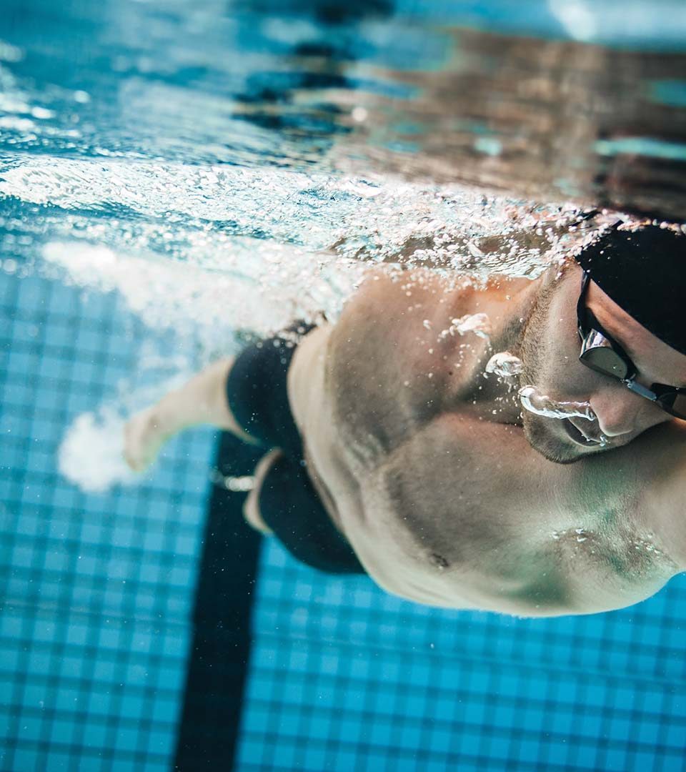 A man swimming underwater in a pool