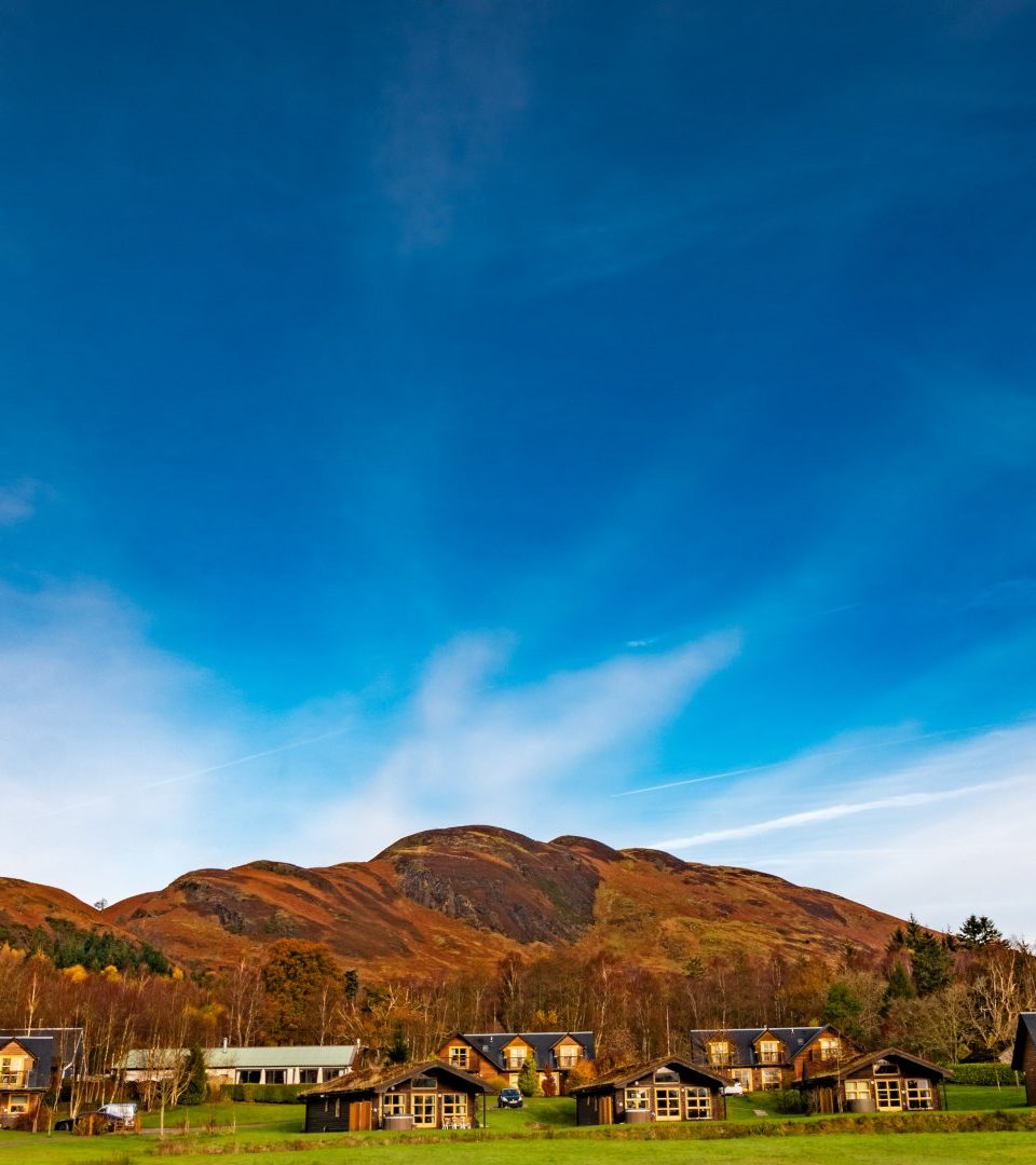 A view of all the lodges and chalets on a bright winters day with Conic Hill behind