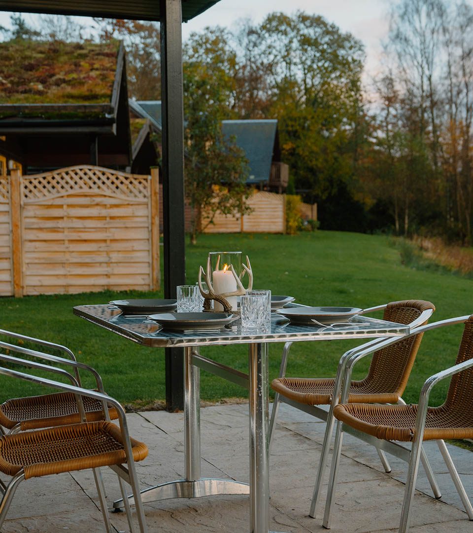 A table set outside on the patio at a chalet at Loch Lomond Waterfront luxury lodges in Balmaha