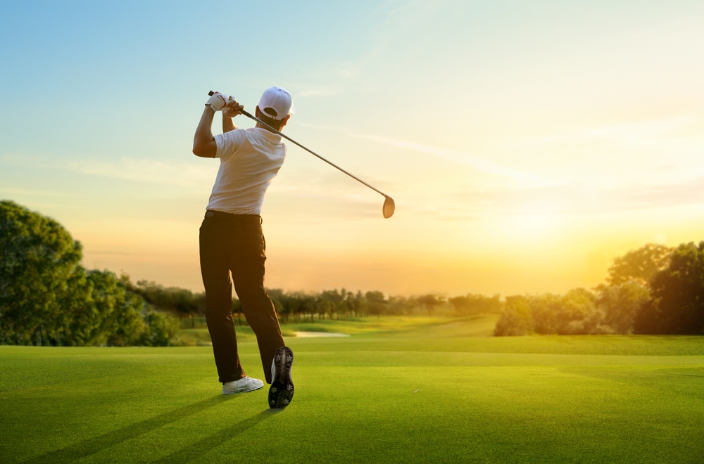 Golfer hit sweeping driver after hitting golf ball down the fairway with sunrise background.