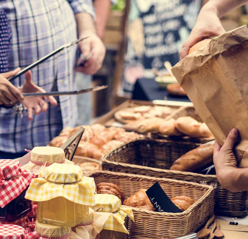 A person with a paper bag prepares to buy some baked goods.