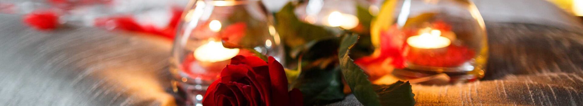 Candles and a red rose on a bed for Valentine's Day.